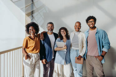 Five diverse friends smiling indoors together.