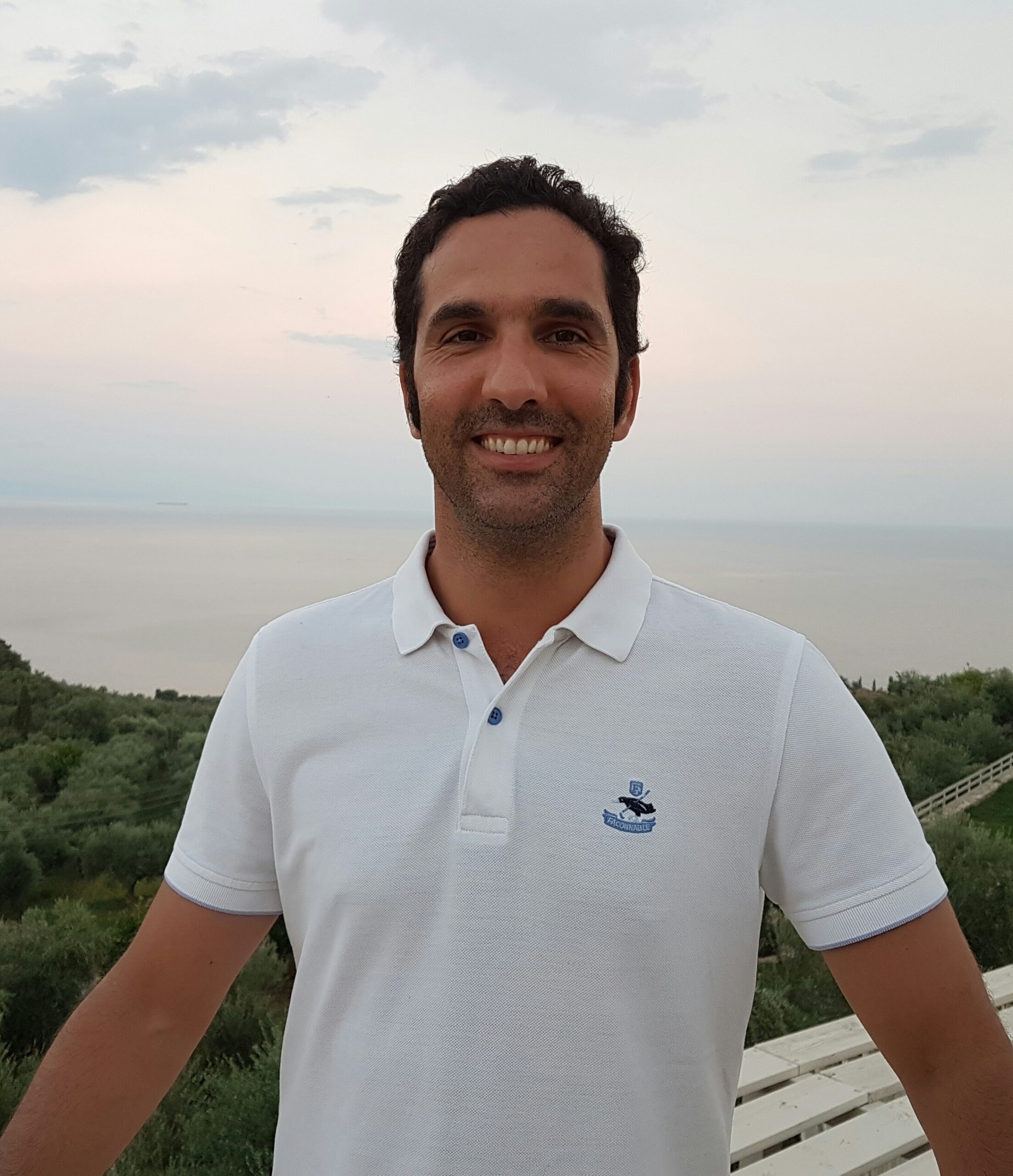 Carlos smiling with ocean and trees in background