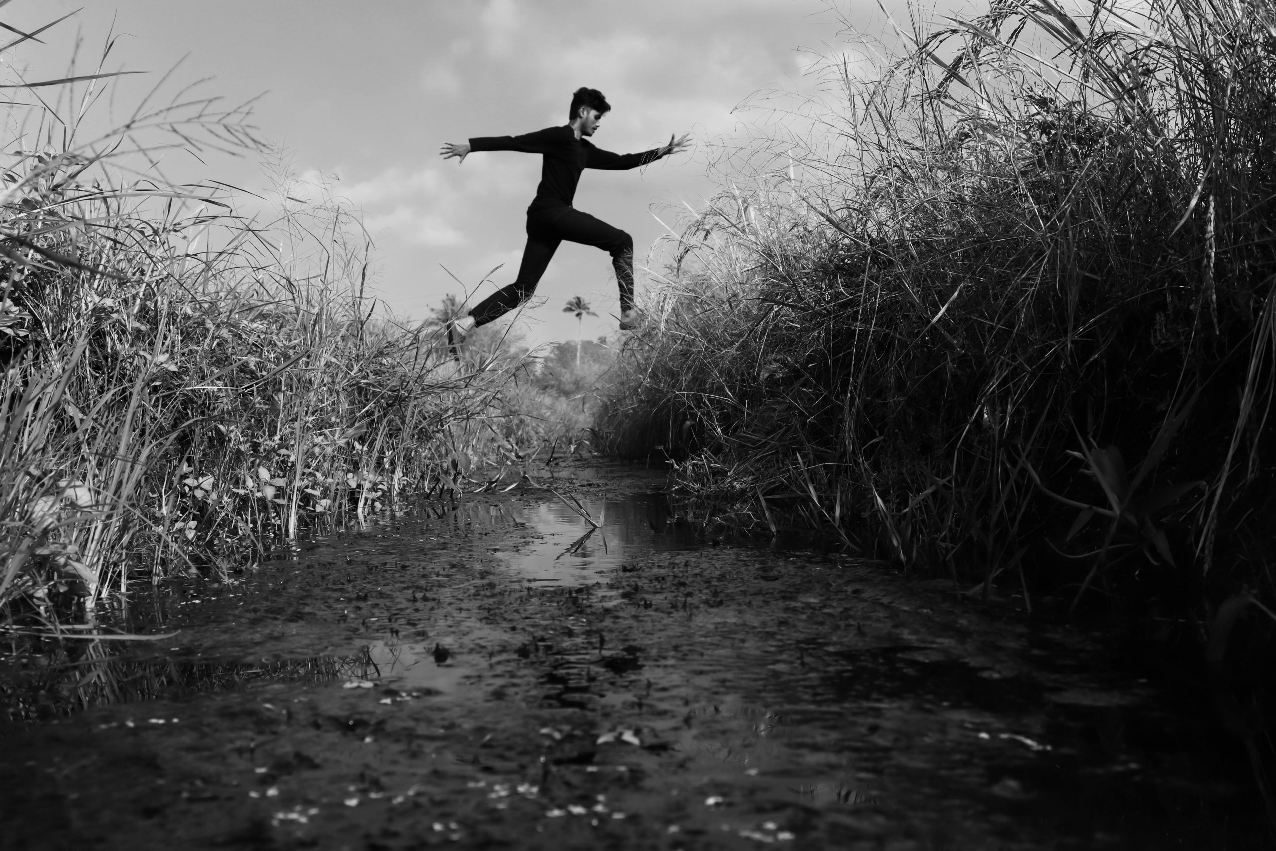Person leaping over a water-filled ditch