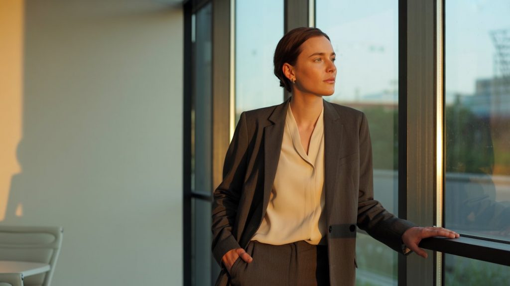 Businesswoman standing by office window at sunset