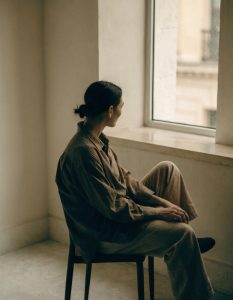 Person sitting by window, gazing outside thoughtfully
